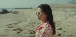 Indonesian singer NIKI on beach with round, long sunglasses for Oceans and Engines music video