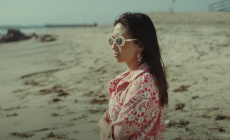 Indonesian singer NIKI on beach with round, long sunglasses for Oceans and Engines music video