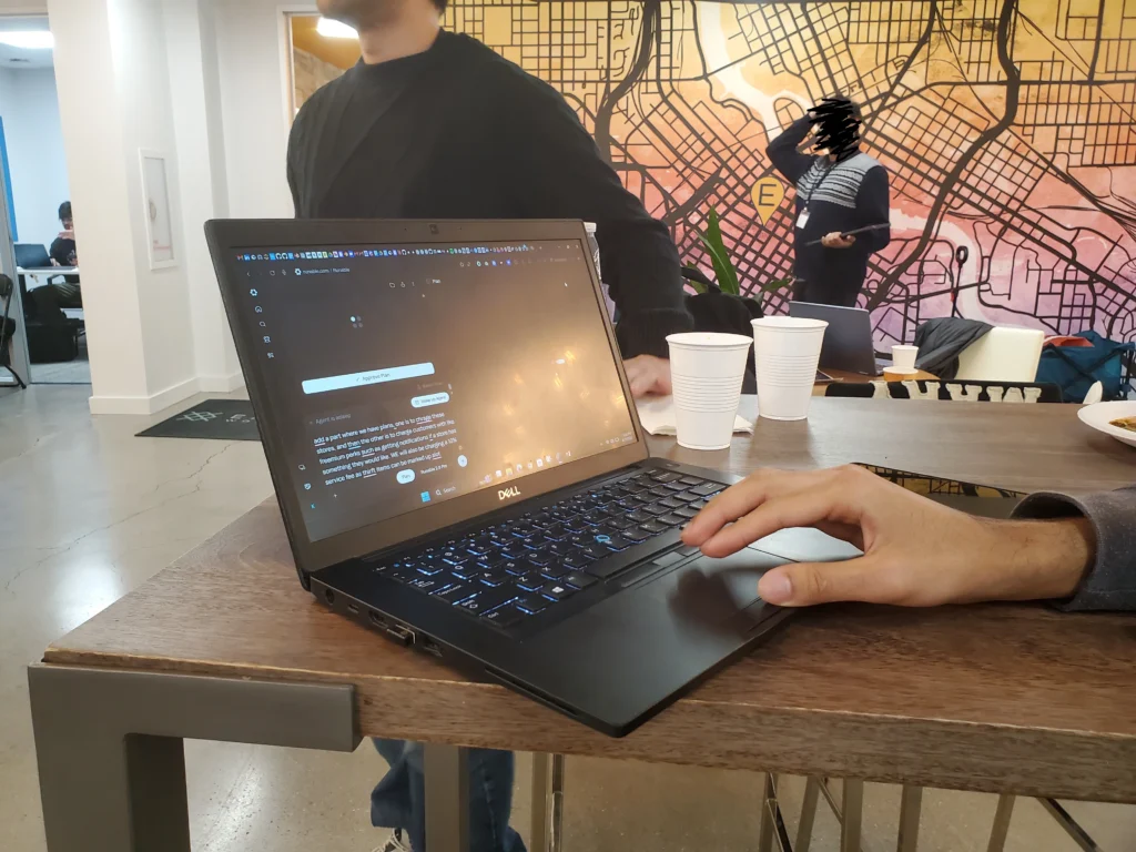 Black Dell laptop with a hand hovering over the trackpad as a vibe coding user puts a prompt into Runable, a generative AI agent